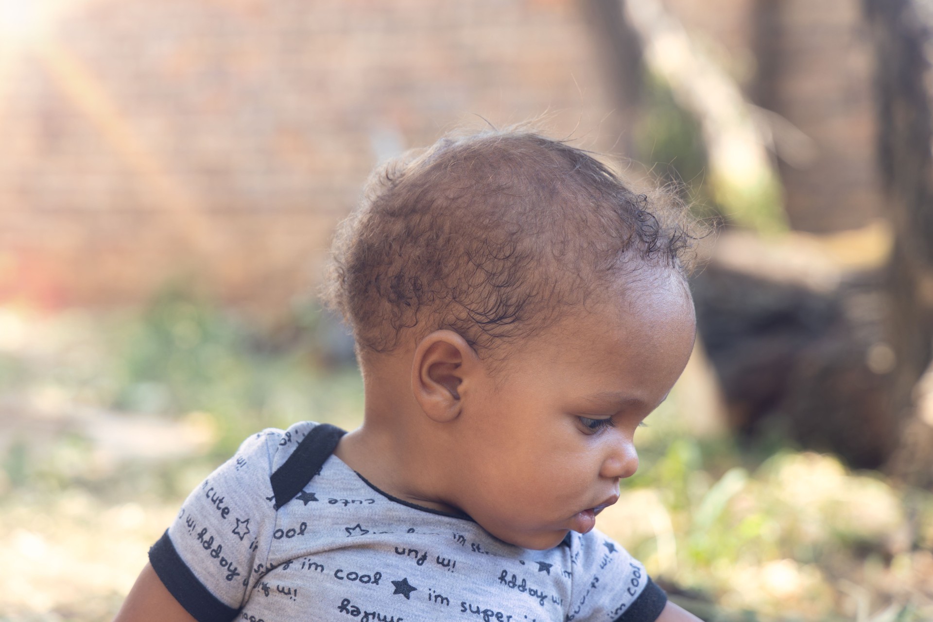 african baby playing in front of the house in the late afternoon, sunny day