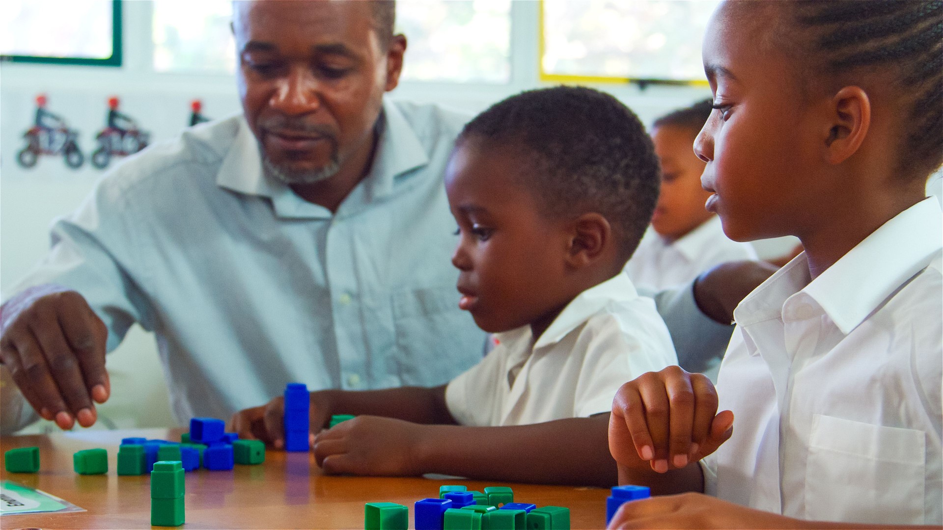 Teacher Assists Students With Building Blocks in Classroom Activity